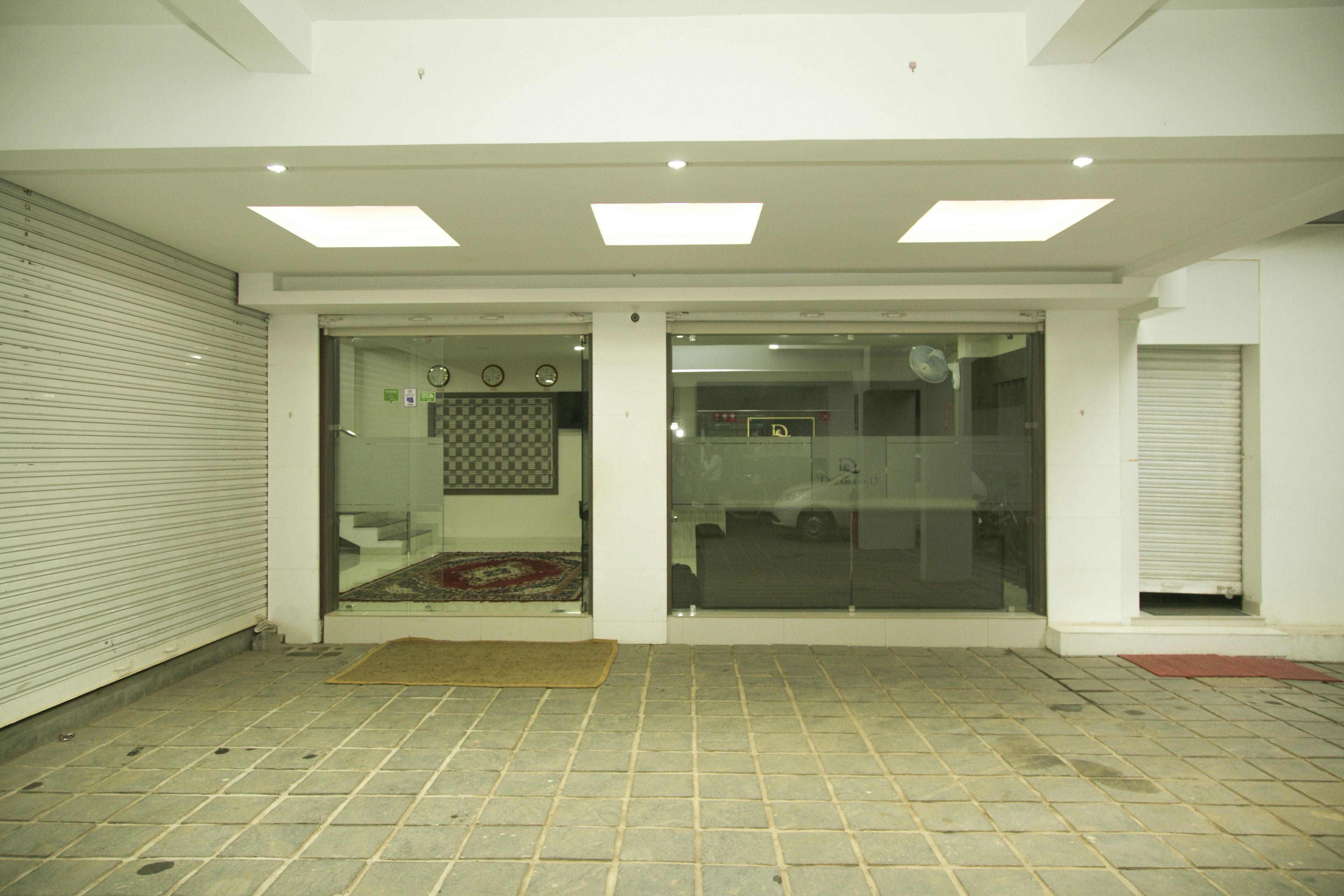 A closed storefront with a tiled floor, a glass door, and a small rug in front.