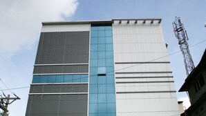Um edifício moderno com fachada de vidro extensa, uma placa de destaque com a inscrição 