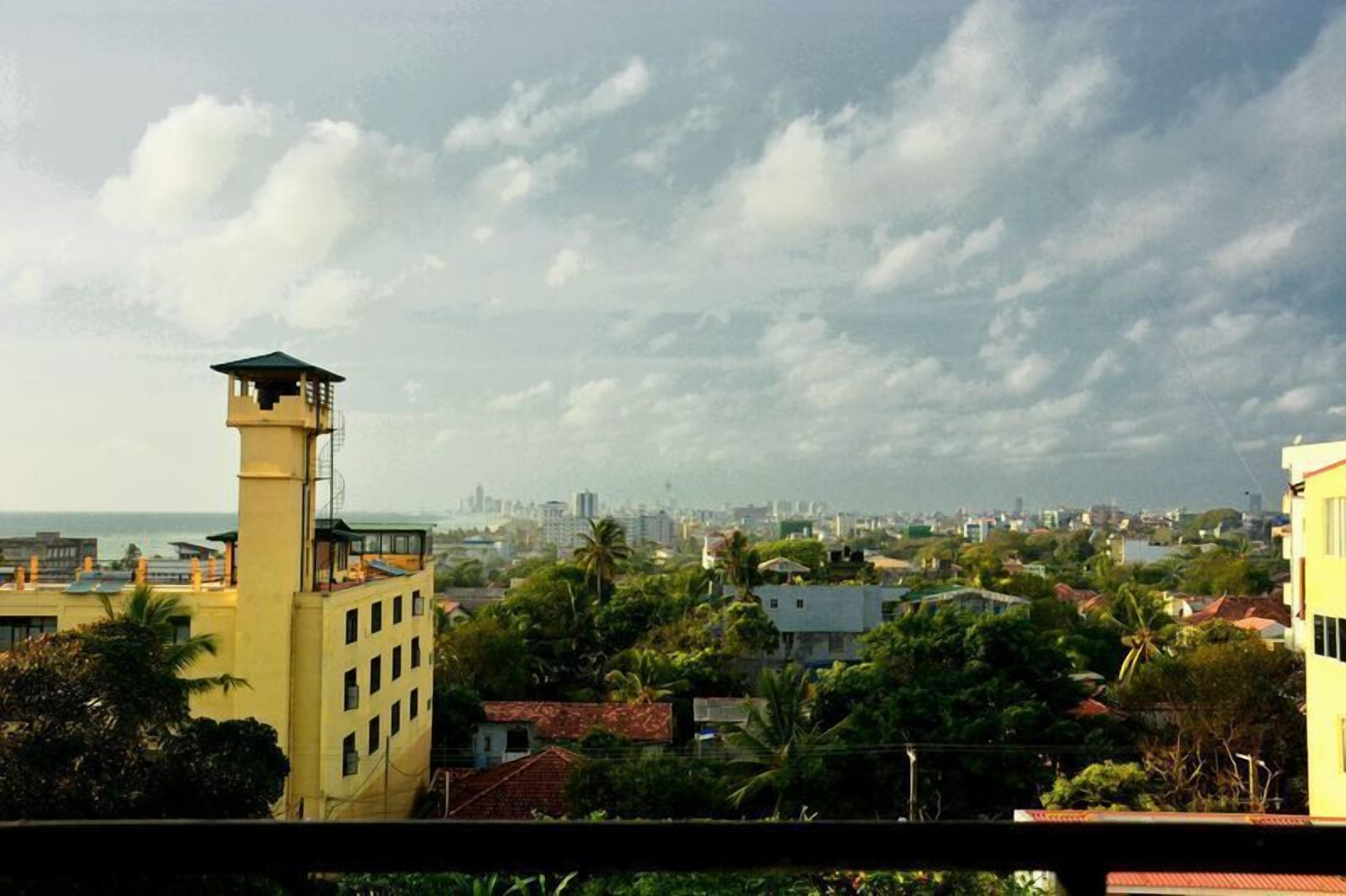 A coastal cityscape with a prominent yellow building featuring a tower and a balcony.