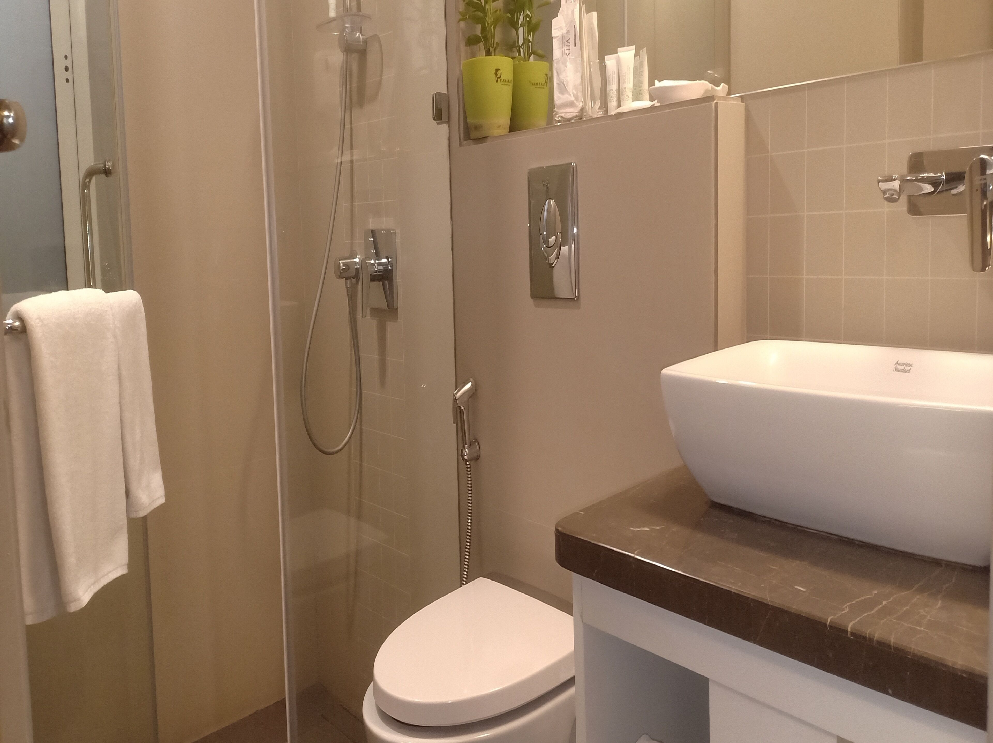 Un baño con ducha de vidrio, inodoro blanco y lavabo de mármol.