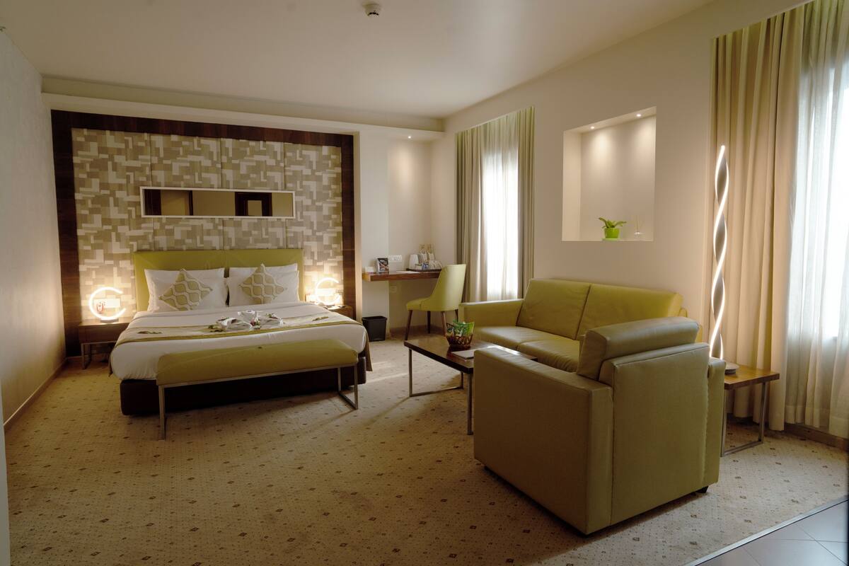 Una habitación de hotel con cama, sofá, escritorio y una silla.