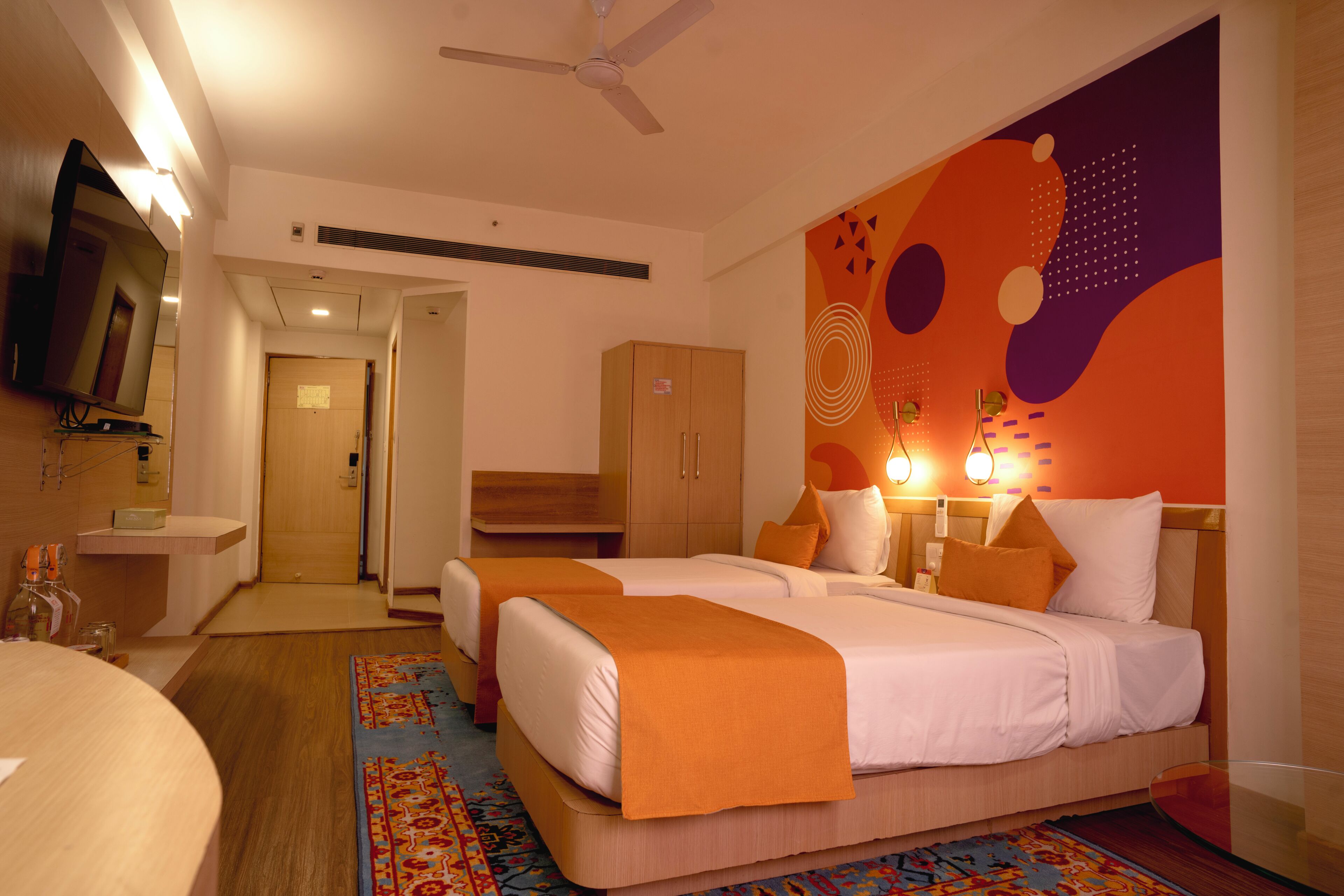 A hotel room with two beds, a TV, a desk, and a bathroom.