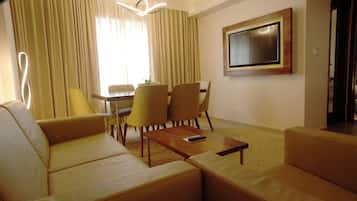 A modern living room with a sofa, chairs, a coffee table, a TV, and a dining area with a table and chairs.