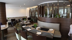 A modern restaurant with a curved seating area, a reserved section, and a view of the interior through a glass partition. - IRA By Orchid Bhubaneswar (Bhubaneshwar)