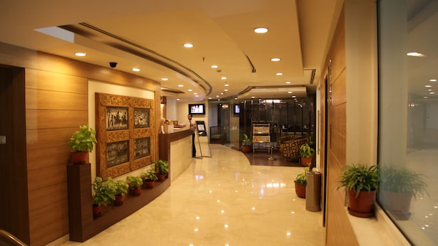 A hotel lobby with a reception desk, potted plants, a large window, and a curved ceiling with recessed lighting. - IRA By Orchid Bhubaneswar (Bhubaneshwar)