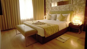 A hotel room with a bed, bedside table, lamp, and a bench. - IRA By Orchid Bhubaneswar (Bhubaneshwar)