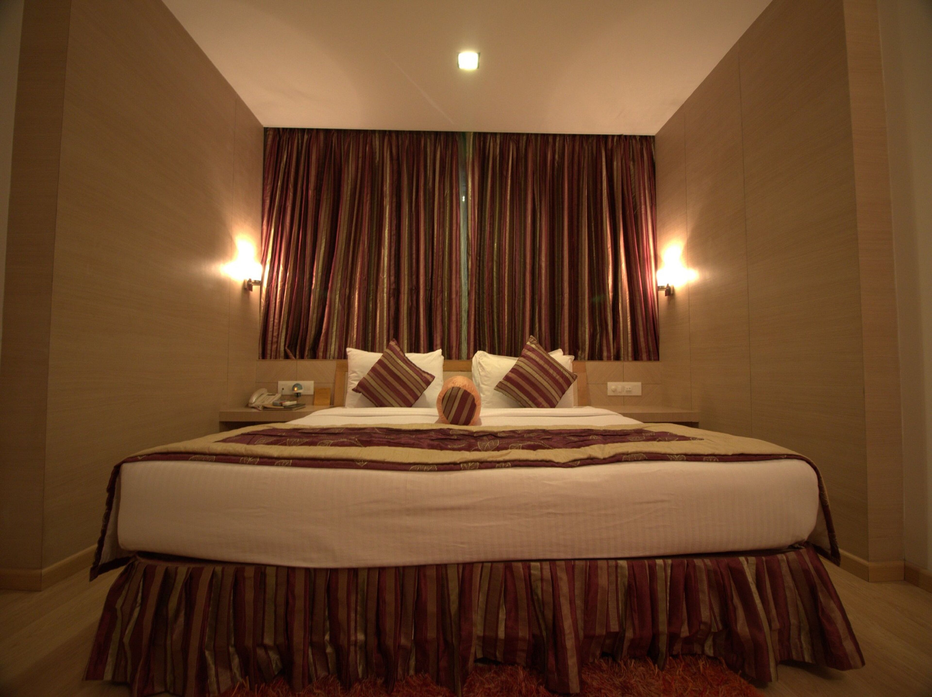A hotel room with a large bed, two bedside lamps, a telephone, and a mirror on the wall.
