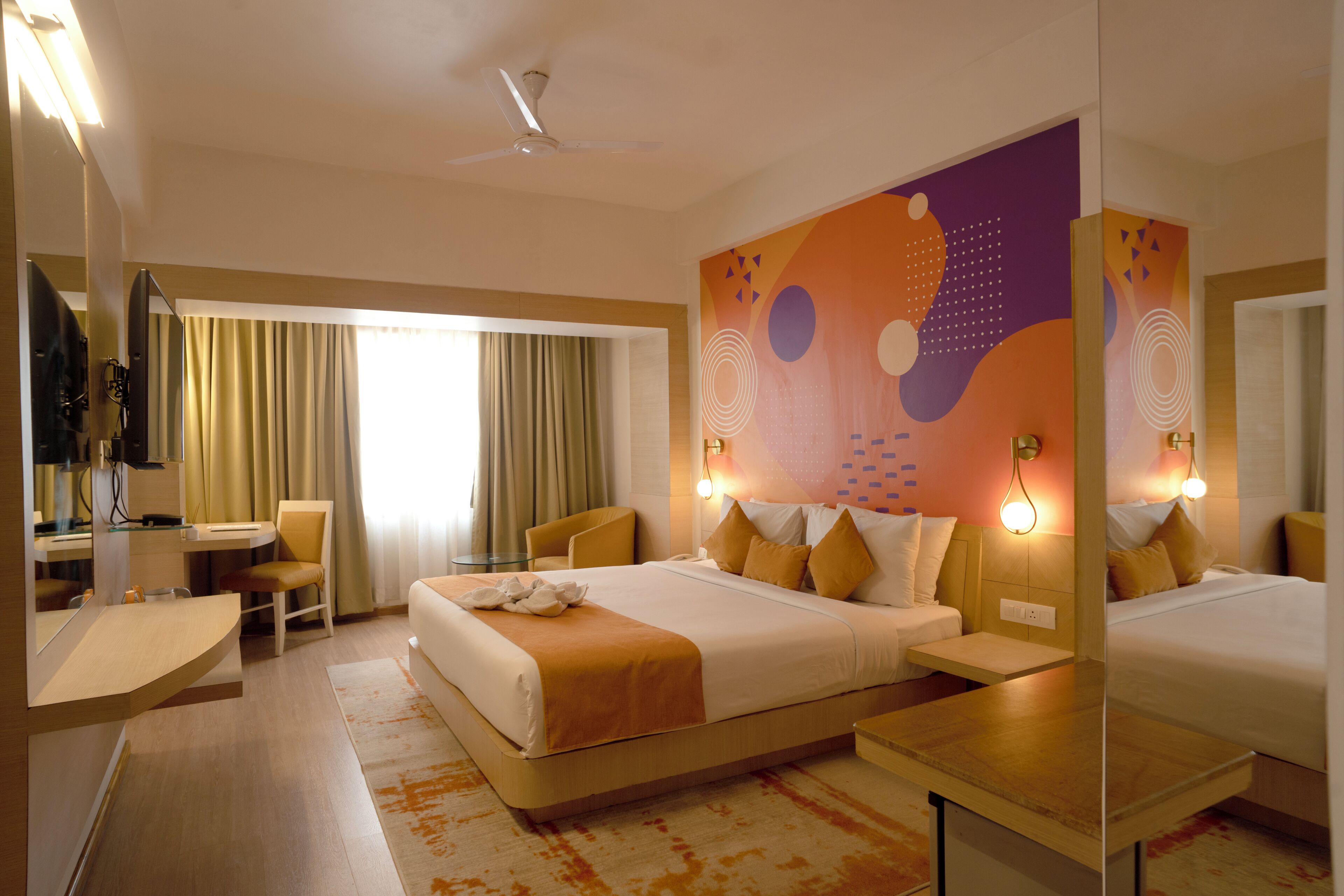 Una habitación de hotel con una cama, un escritorio, una silla y un espejo grande.