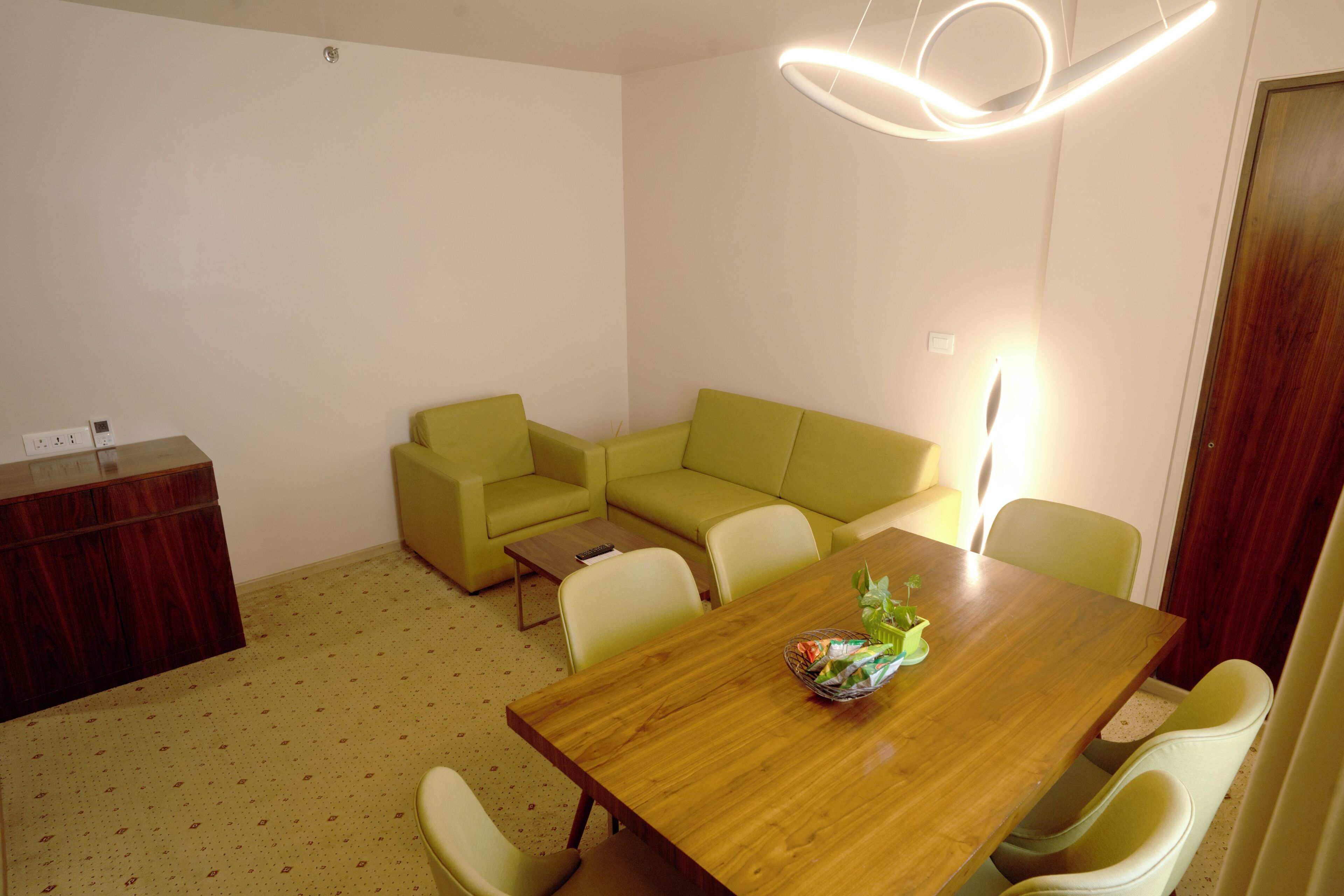 A room with a wooden dining table, a green sofa, and a wooden cabinet.