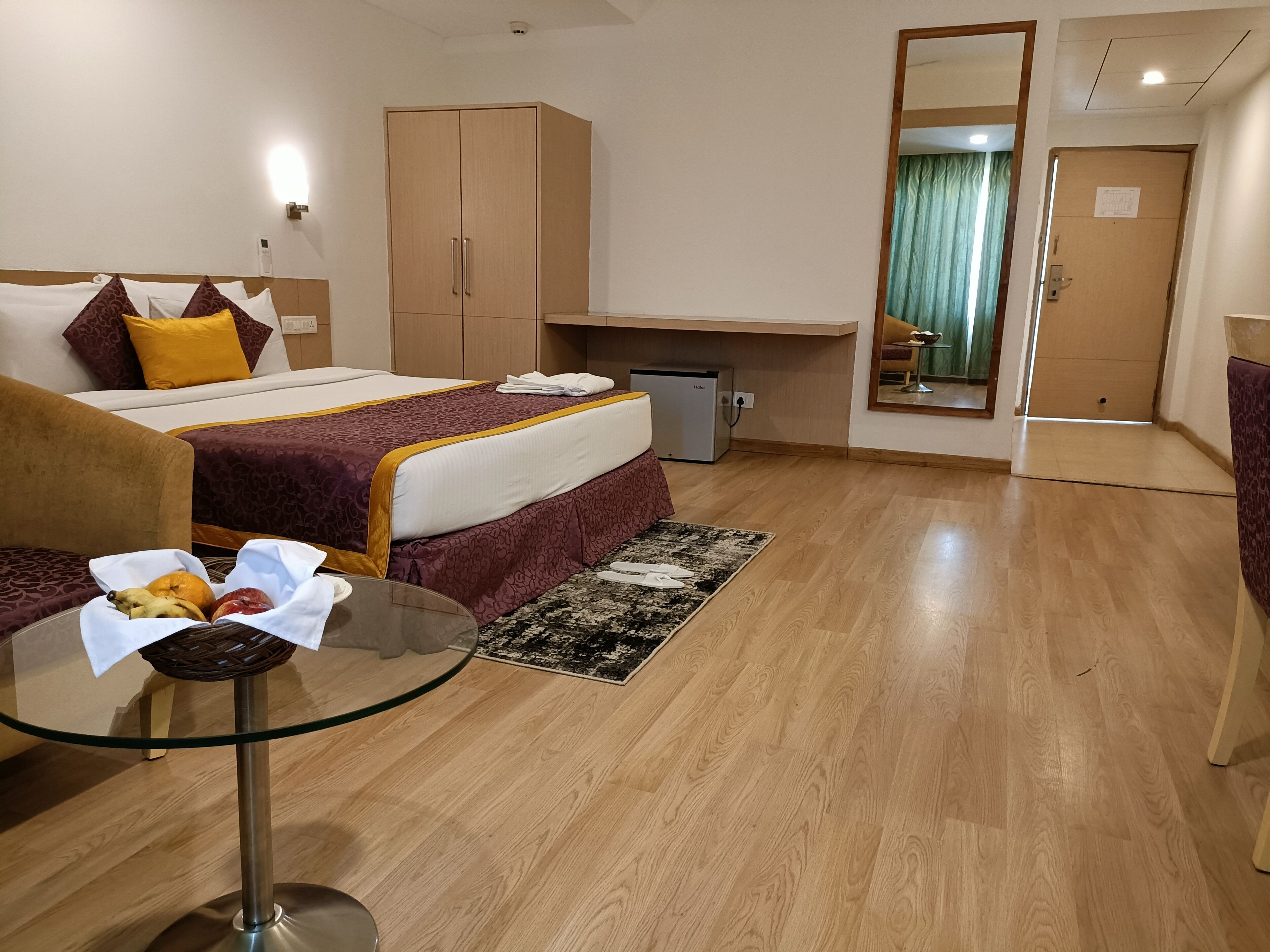 Habitación de hotel con cama, escritorio, armario y una pequeña mesa con frutas.