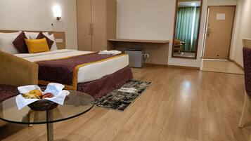 Habitación de hotel con cama, escritorio, armario y una pequeña mesa con frutas.