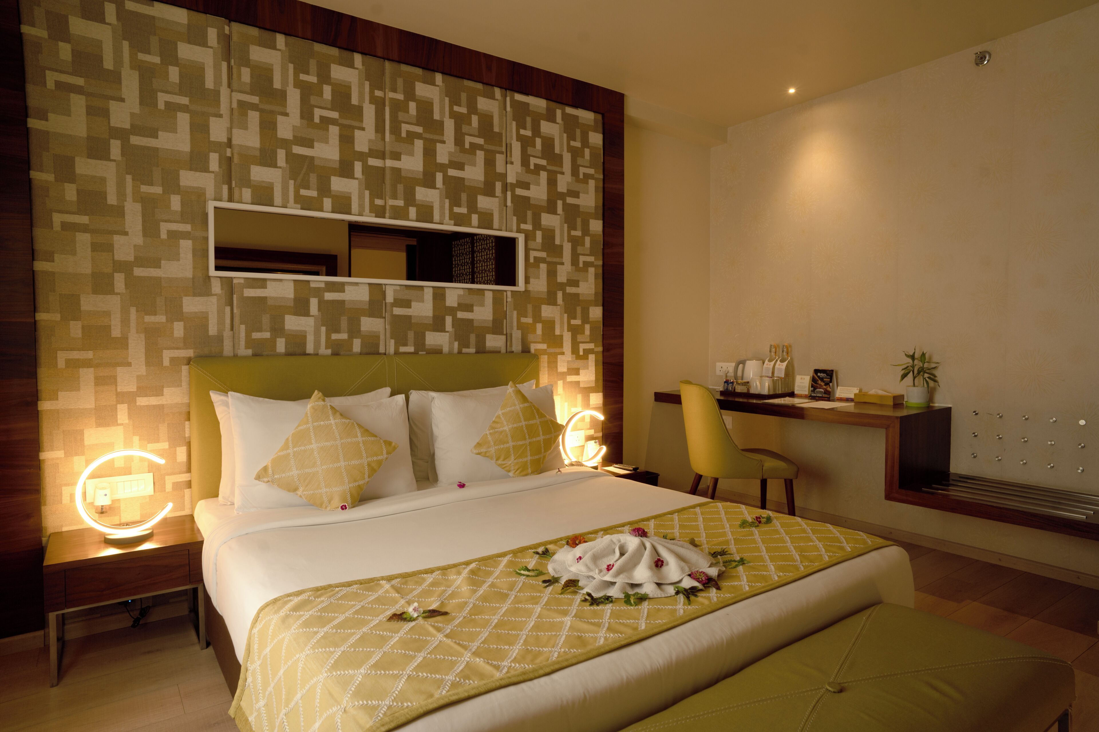 A hotel room with a large bed, bedside lamps, a desk with a chair, and a wall-mounted TV.