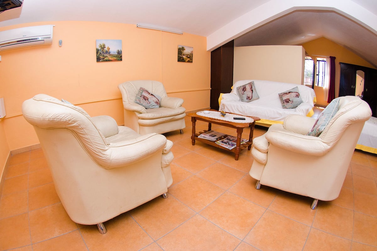 Un salon chaleureux avec deux canapés de couleur crème, une table basse en bois et un fauteuil blanc.