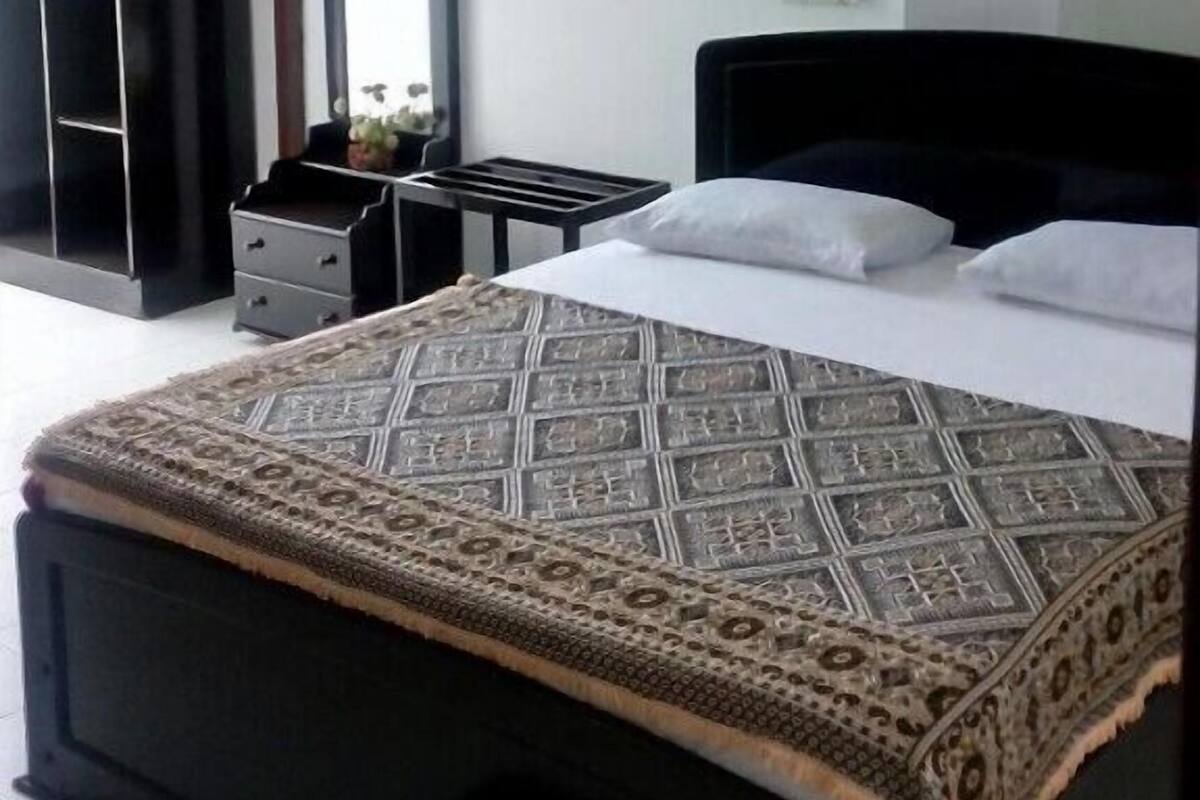 A bedroom with a bed, a dresser, a mirror, and a wardrobe.