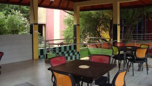 An outdoor cafe with tables and chairs, a staircase, and a view of trees and buildings. - Hotel Mahawasala (Dambulla)