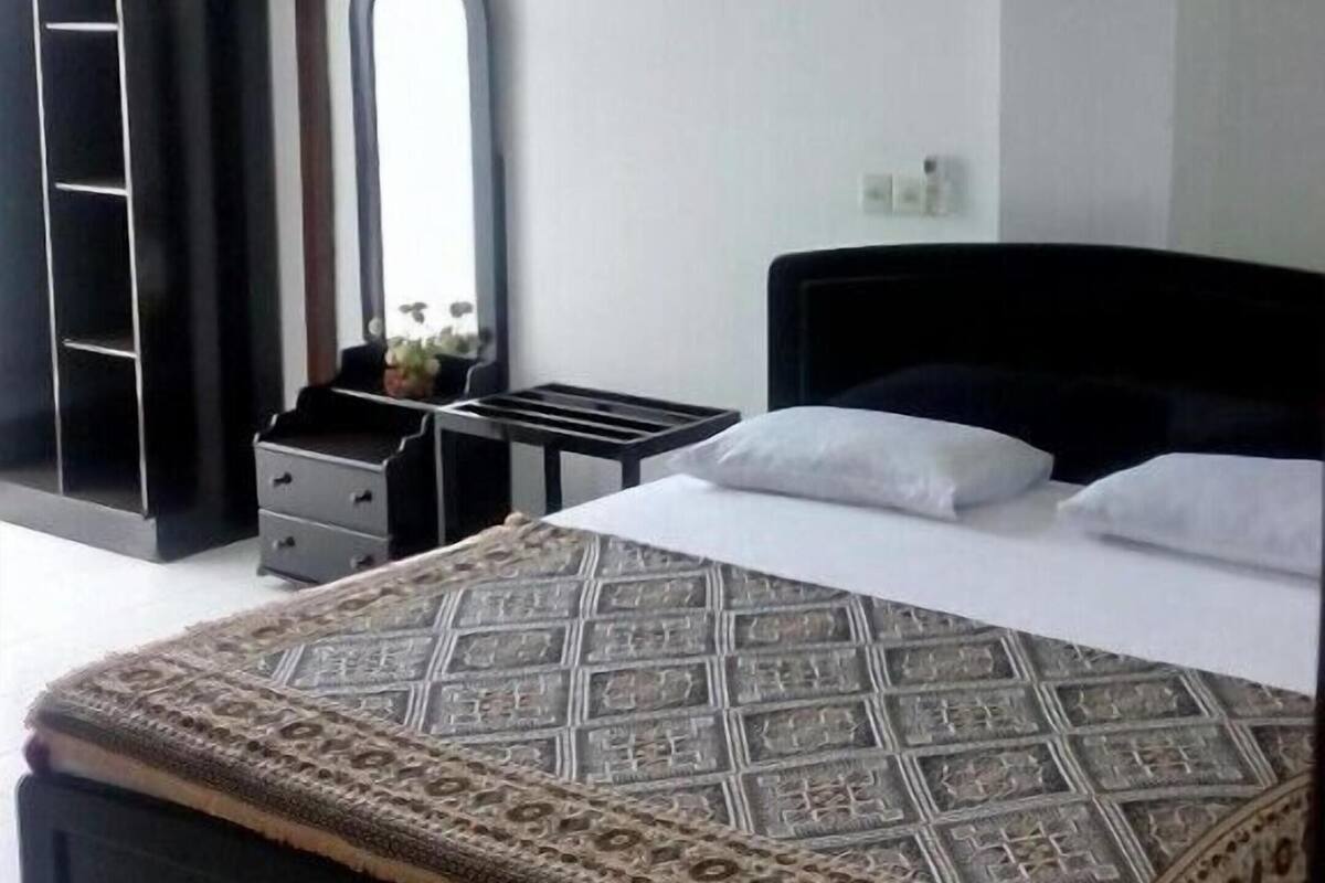 A bedroom with a bed, a dresser, a mirror, and a wardrobe.