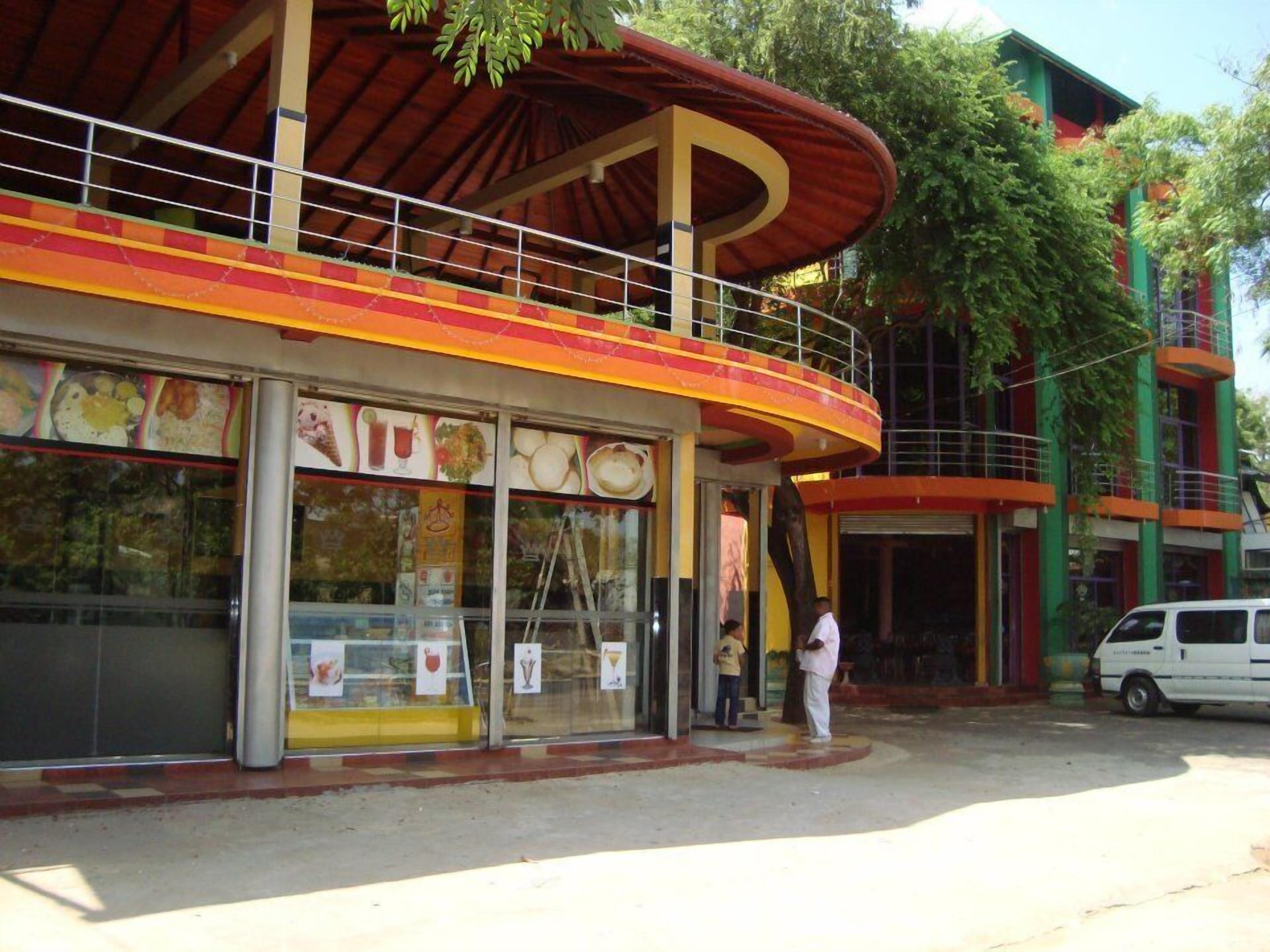 A restaurant with a curved roof and a glass facade displaying food items.