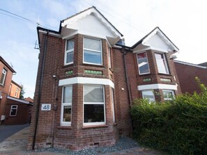 A two-story brick house with a bay window on the ground floor and a dormer window on the second floor.