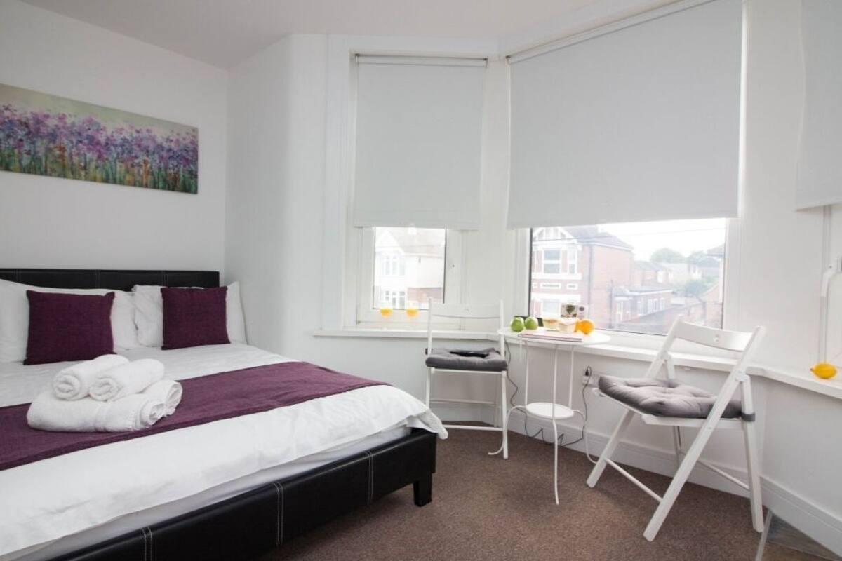 A neatly arranged hotel room with a bed, a desk, and a chair.