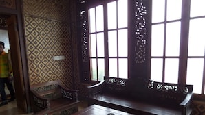A traditional room with patterned walls, a wooden bench, and a table. - Pondok Wisata Adas (Ngadisari)