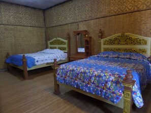 A room with two wooden beds, one with a blue floral bedspread and the other with a white and blue patterned bedspread. - Pondok Wisata Adas (Ngadisari)