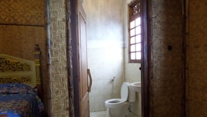 A small, narrow room with a bed on the left and a toilet in the center. - Pondok Wisata Adas (Ngadisari)