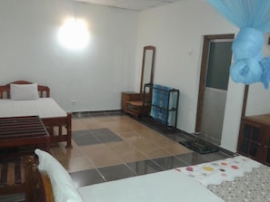 Ein Zimmer mit einem Bett, einem Holzstuhl, einem Tisch, einem Spiegel und einem blauen Baldachin.