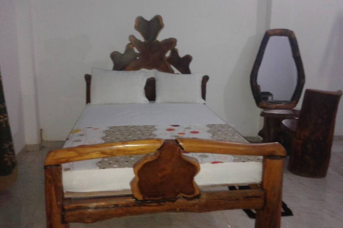 A bed with a wooden headboard and a mirror beside it.