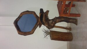 Een houten stoel met een bijzondere geometrische rugleuning en een spiegel bevestigd aan een constructie die op een boom lijkt.