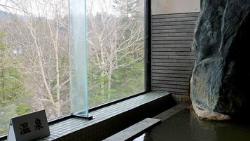 A spa area with a large rock, a window with a view of trees, and a sign with Chinese characters.