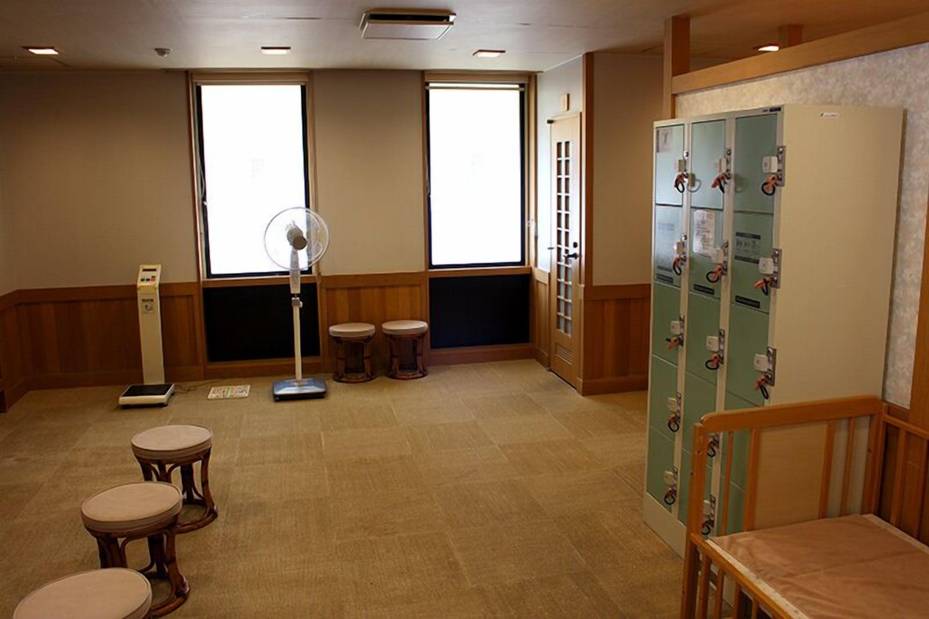 A room with a large window, a standing fan, a scale, and a cabinet with locks.
