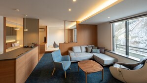 A modern living room with a sofa, armchairs, a coffee table, and a kitchen area with a counter and pendant lights. - Aonobi Yuyu (Biei)