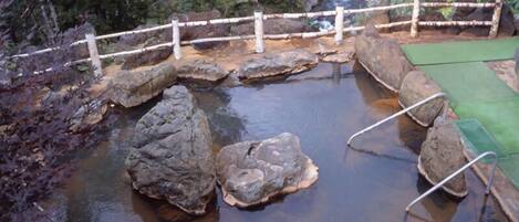 A natural pool with rocks and a wooden bridge.