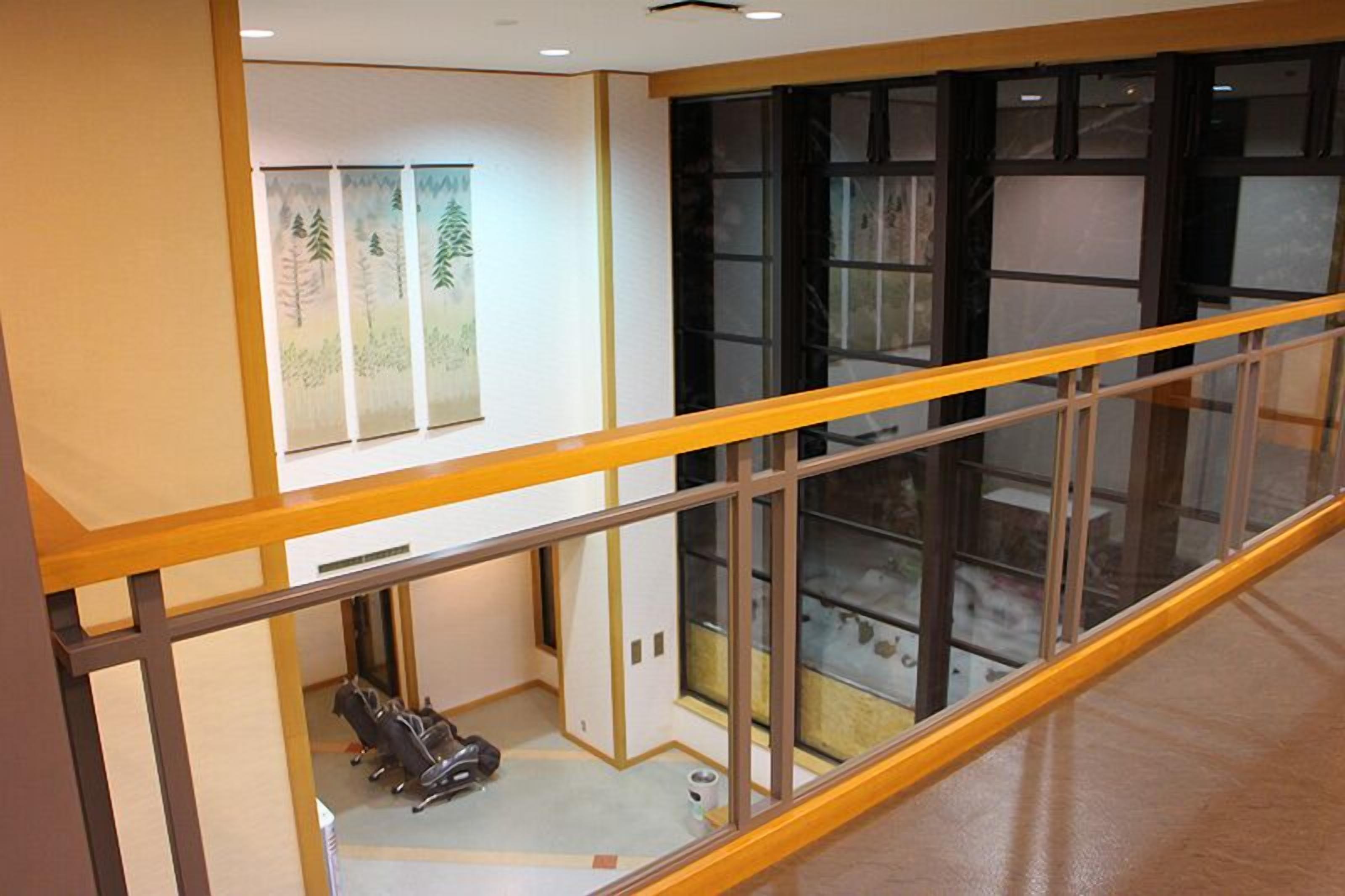 A room with a wooden railing, a large window, and a view of the interior.