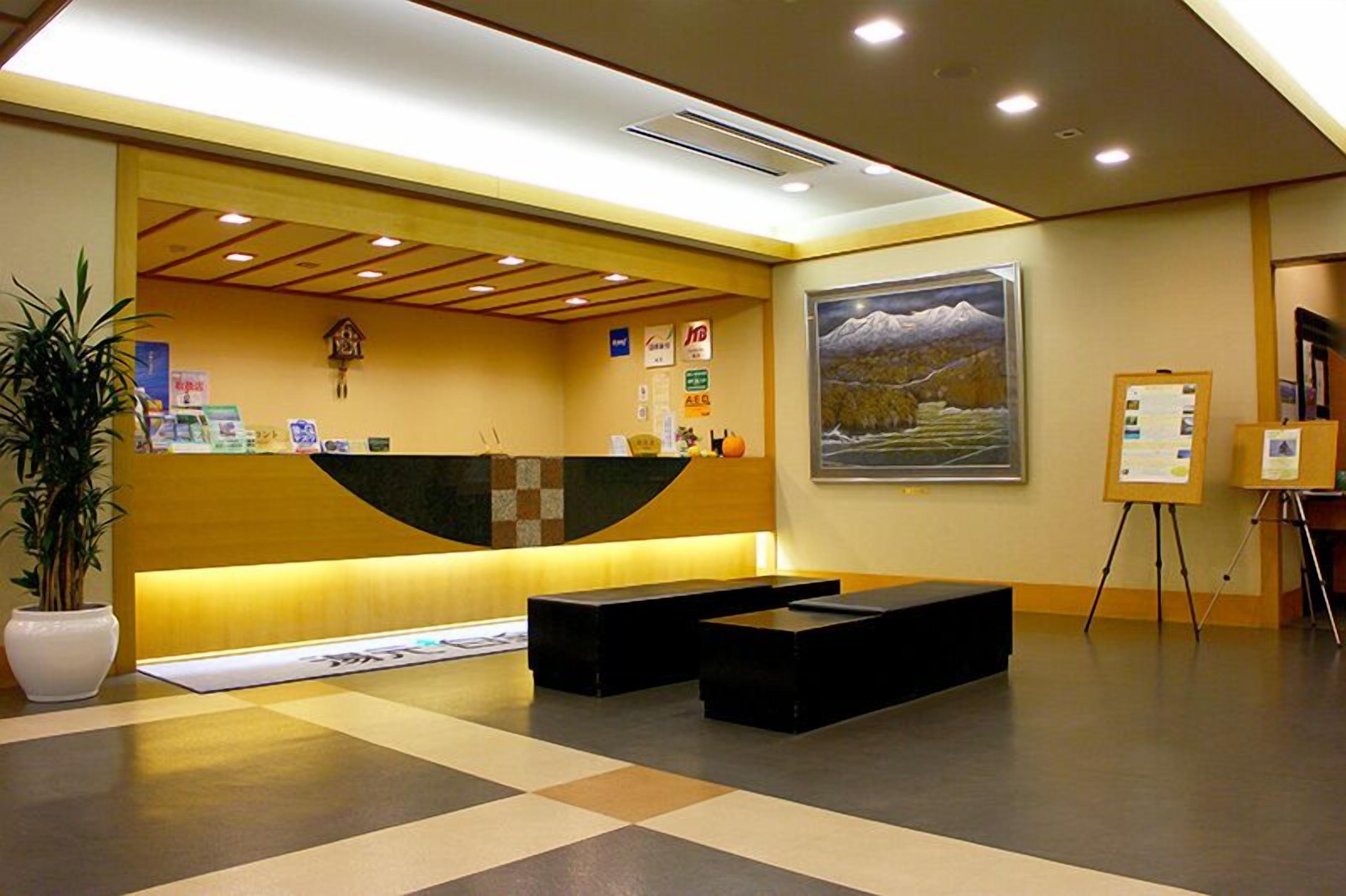 A reception area with a wooden reception desk, a large framed painting, and a potted plant.