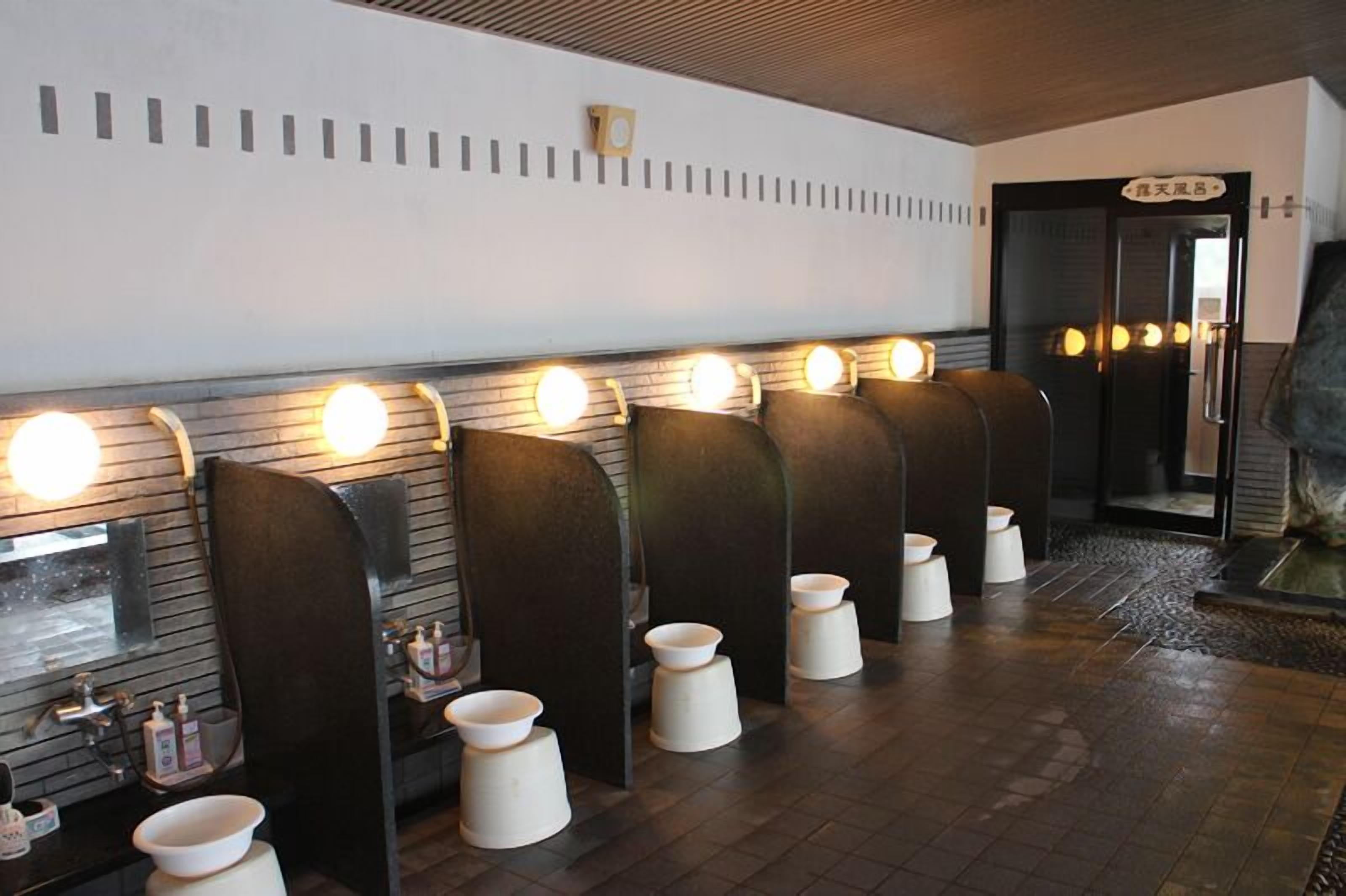 A public restroom with multiple sinks, each with a mirror and soap dispenser.