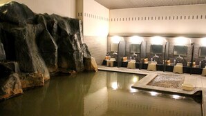 A spa area with a rock formation, a pool, and multiple sinks with mirrors. - Aonobi Yuyu (Biei)