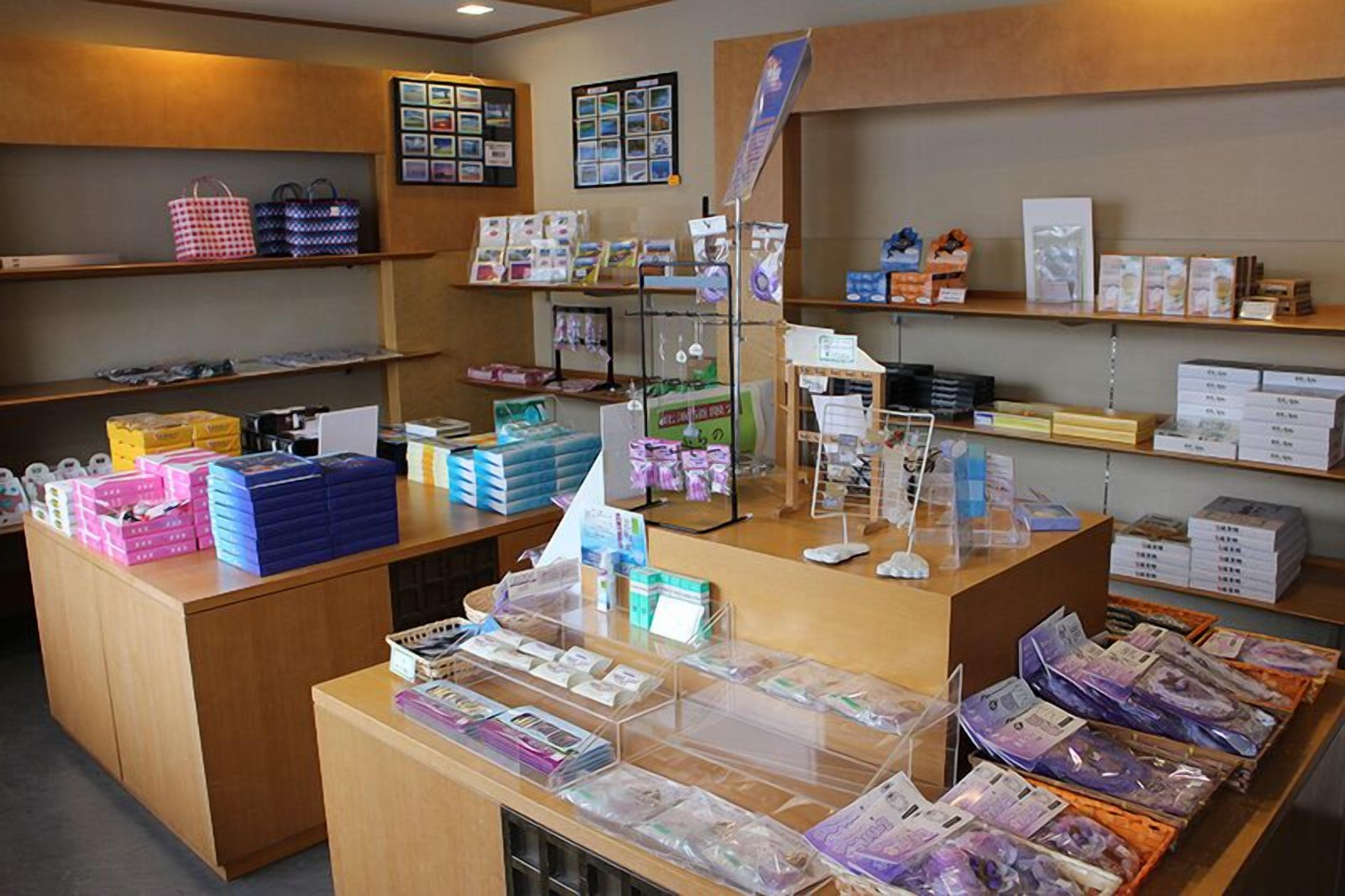 A retail store with shelves stocked with various products, a counter with items for sale, and a display area with promotional materials.