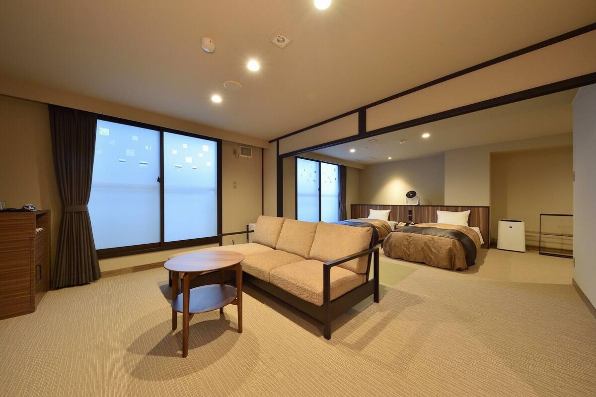 Ein Hotelzimmer mit einer Couch, einem kleinen Tisch, einem Bett und einem Schreibtisch.