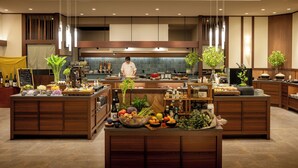 A modern kitchen with wooden cabinetry, a central island with fresh produce, and a chef preparing food. - Aonobi Yuyu (Biei)