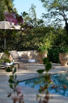 An outdoor pool area with lounge chairs and potted plants.