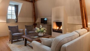 Een gezellige woonkamer met een open haard, een televisie en comfortabele zithoeken.