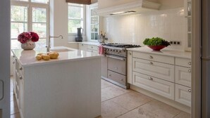Een moderne keuken met witte kastjes, een centraal eiland, een fornuis en een klok aan de muur.