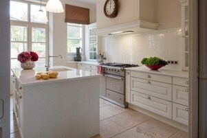 A modern kitchen with white cabinetry, a central island, a stove, and a clock on the wall.