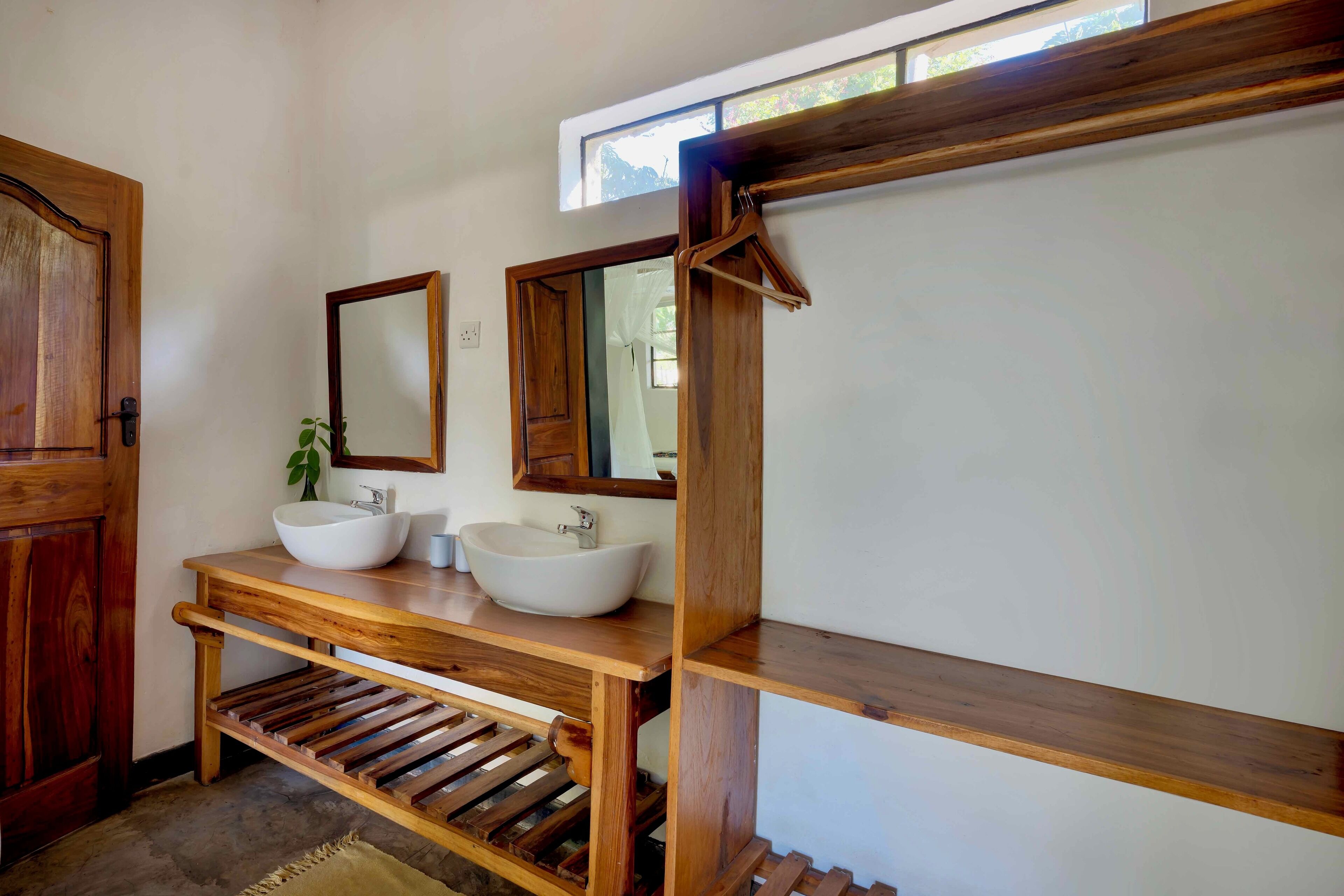 A bathroom with two wooden sinks, a mirror, and a wooden shelf.
