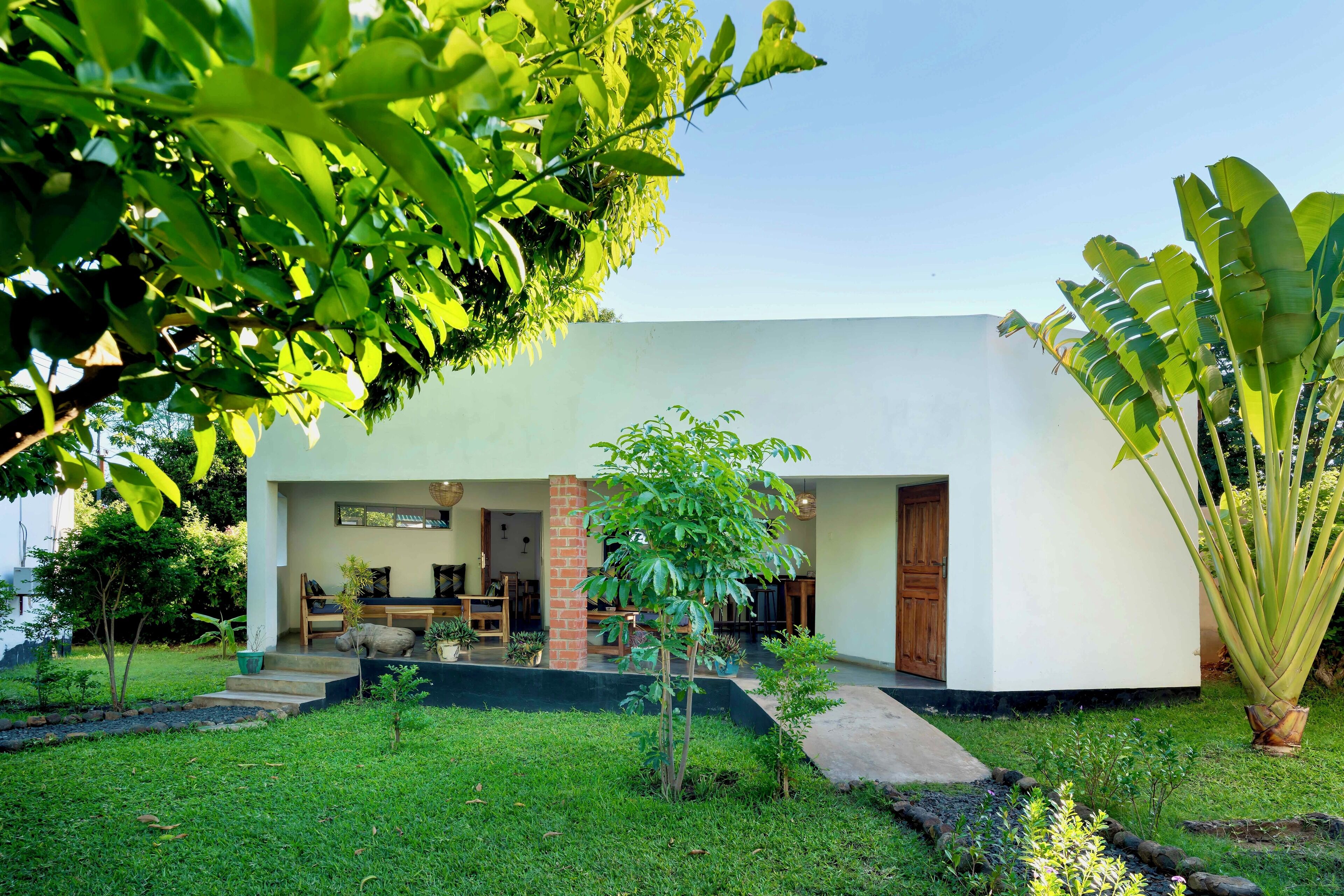 Une maison moderne dotée d’un patio, d’un petit jardin et d’une porte en bois.