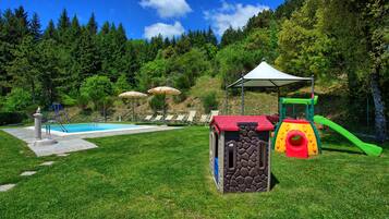 Relax by the pool, surrounded by lush greenery and a children's play area.