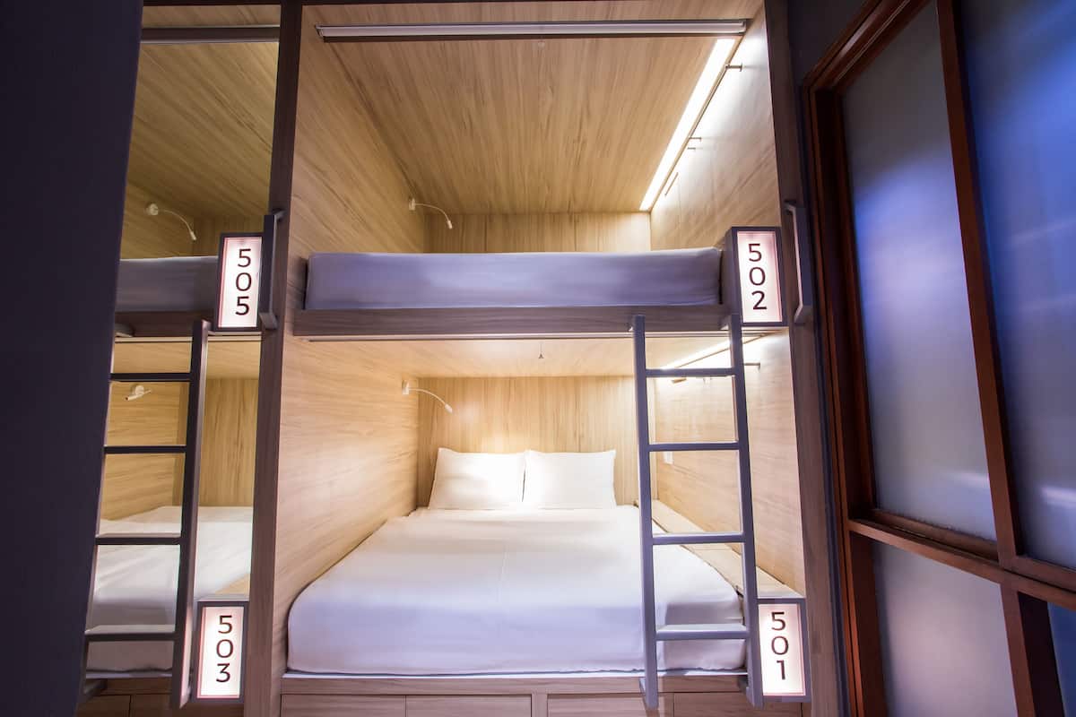 A bunk bed room with wooden walls and a ladder. Each bunk has a number sign above it.