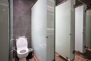 Un baño moderno con inodoro blanco, separador de vidrio y zona de ducha.