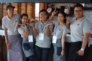 A group of people in a kitchen area with wooden cabinets and a tiled backsplash.